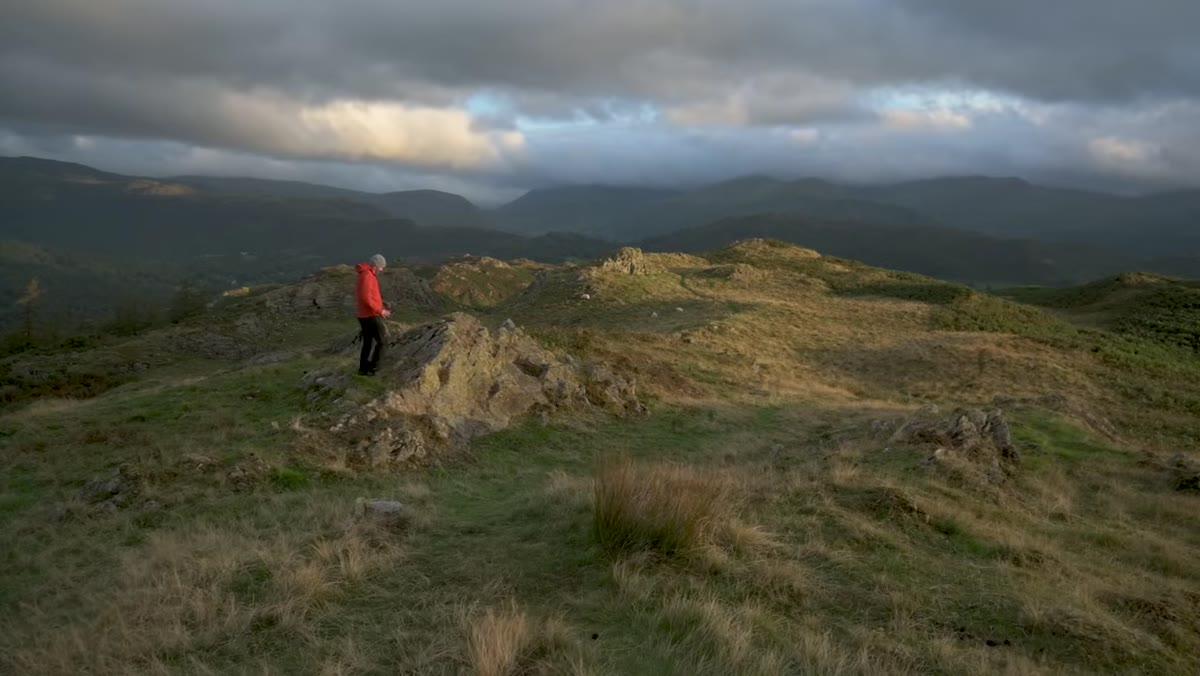 Sunlit rocks and grass in the foreground with valley behind