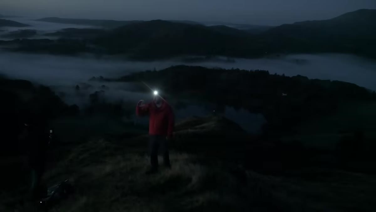 Danson pointing toward horizon where sunrise light will enter valley