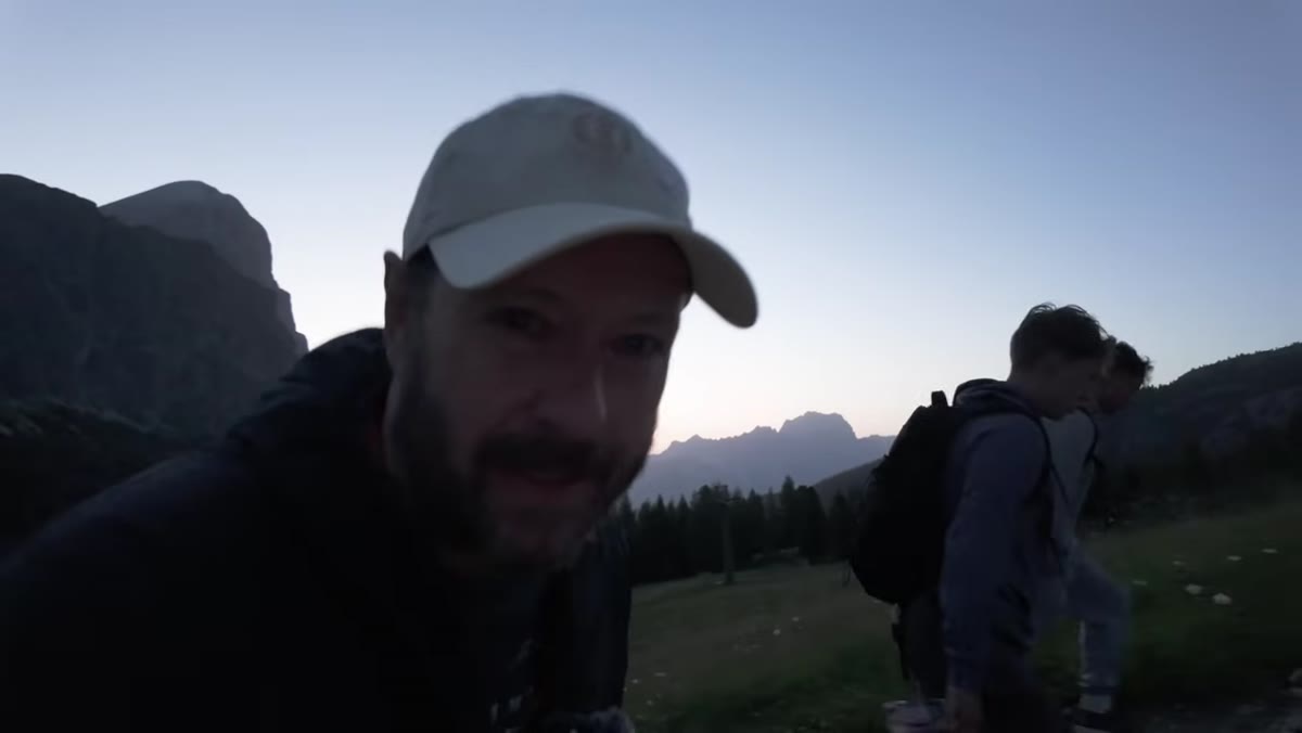 Danson hiking uphill toward dramatic Dolomite ridgeline at dawn