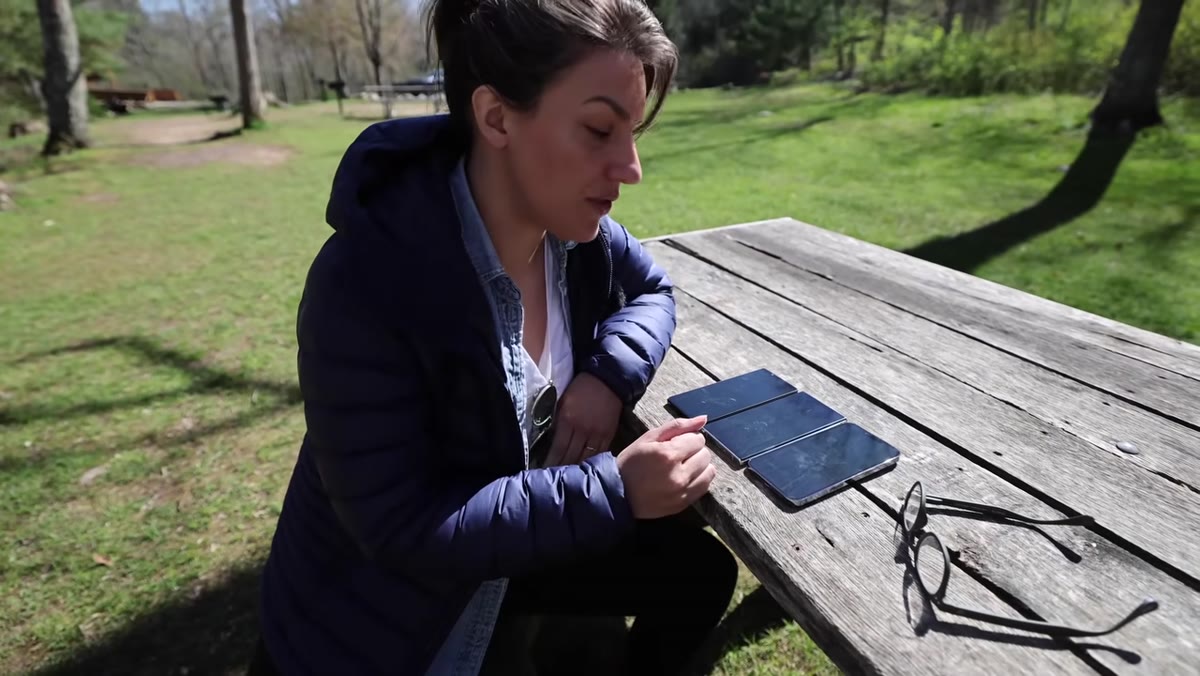 All three phones held in sunlight showing screen visibility