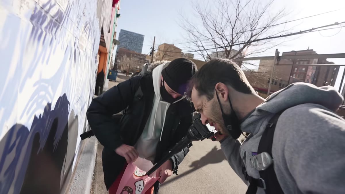 Joey holding a donut while Pierre shoots through the donut hole